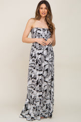 woman wearing a black and white tropical leaf print strapless smocked maternity maxi dress