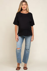 Pregnant woman wearing a black short sleeve maternity t-shirt and distressed blue jeans