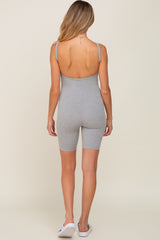 Back view of a woman wearing a grey ribbed sleeveless romper with a scoop back and biker short length