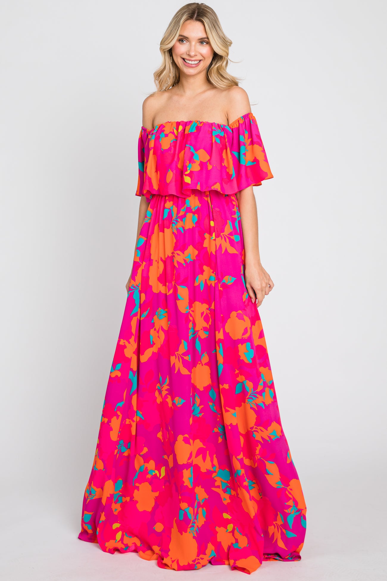 woman wearing a pink off-the-shoulder floral maxi dress with orange and teal patterns