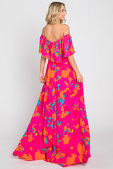 woman wearing a pink off-the-shoulder floral maxi dress with orange and teal patterns
