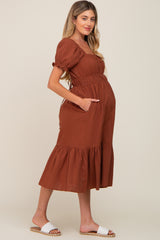 pregnant woman in a rust brown puff sleeve maternity midi dress with pockets and white sandals