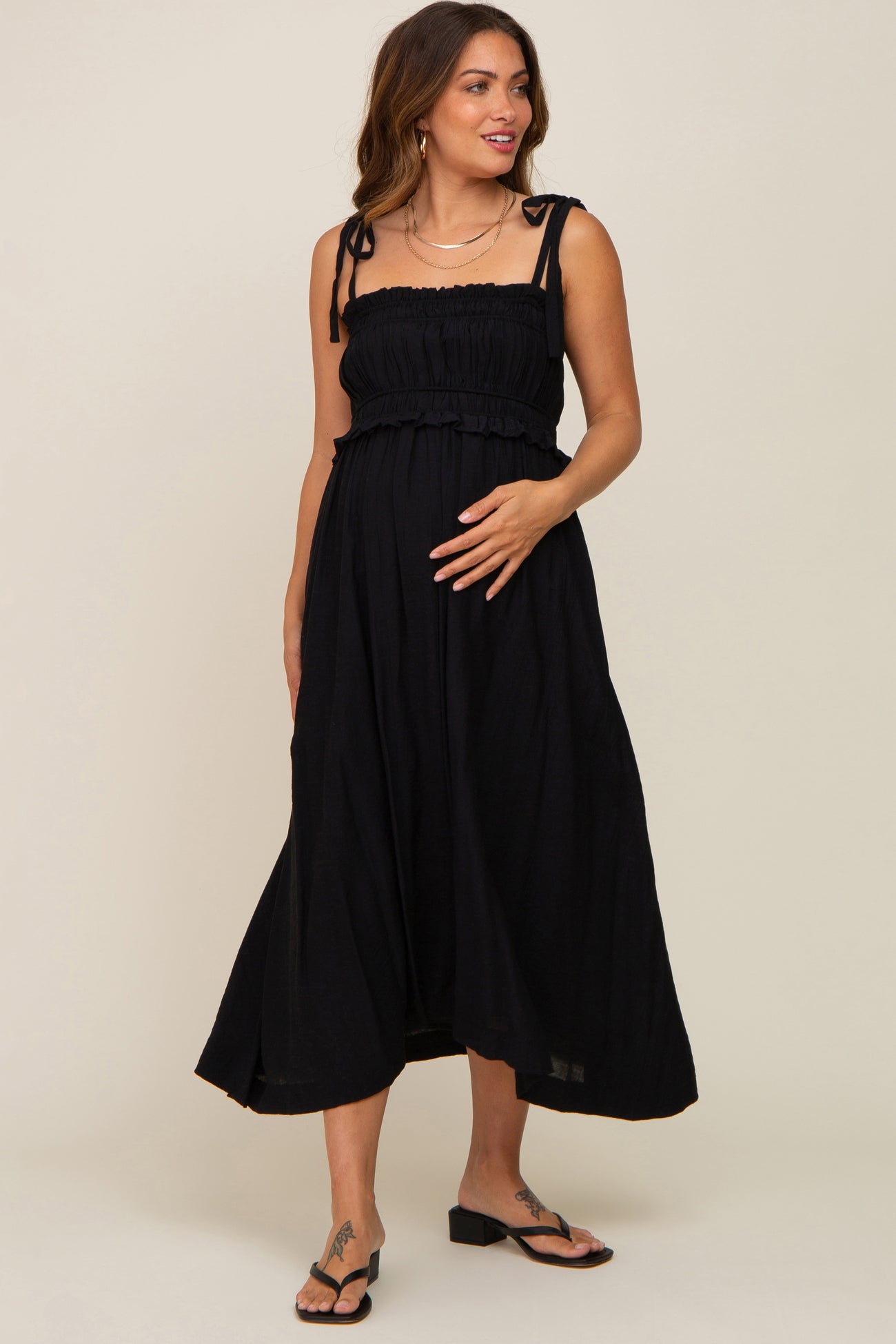 pregnant woman wearing a black smocked maternity midi dress with tie straps and sandals