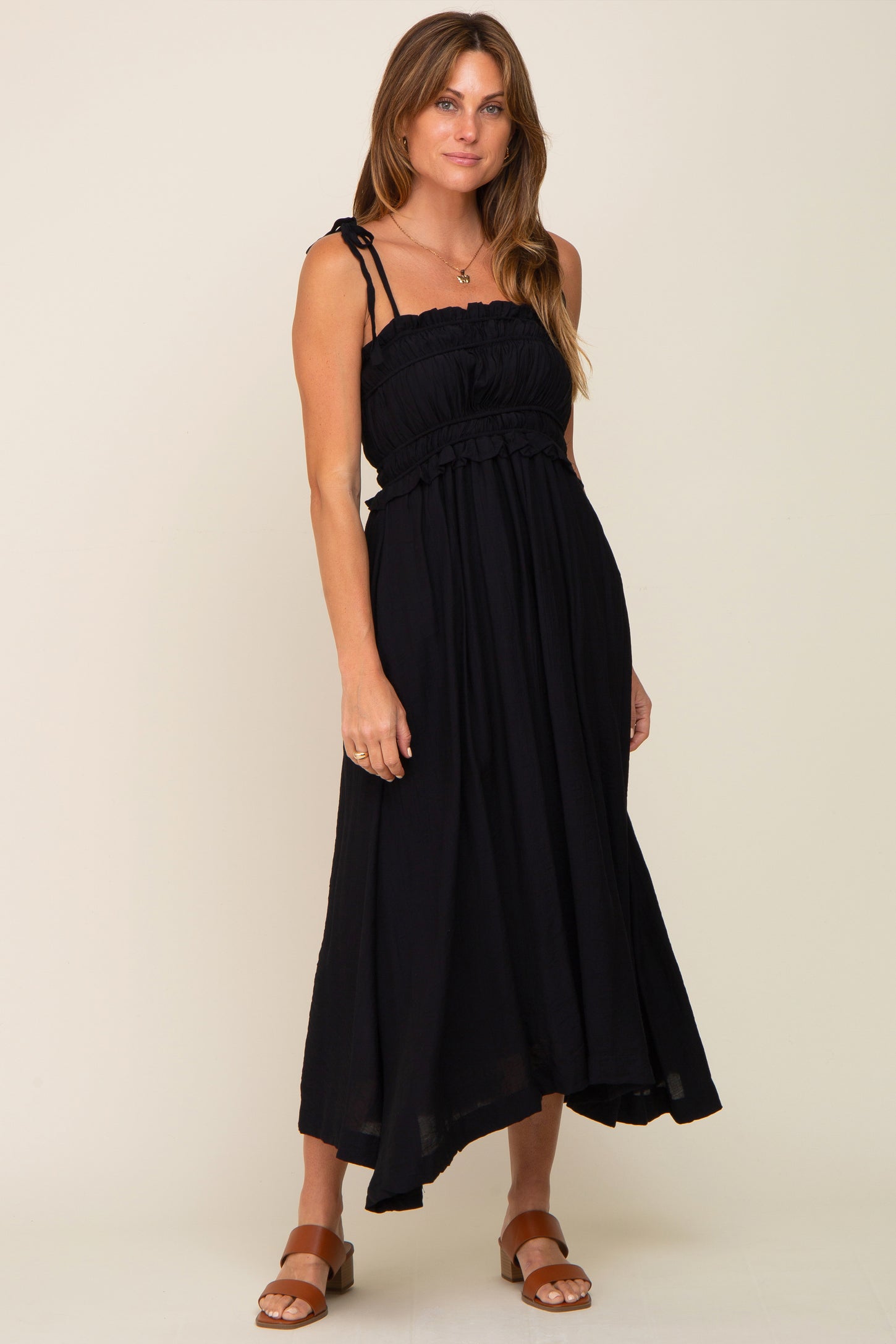 woman wearing a black smocked midi dress with tie straps and brown leather sandals
