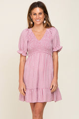 woman wearing a pink and white gingham smocked mini dress with puff sleeves and a ruffled hem