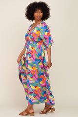 woman wearing a colorful maxi dress with leaf patterns and a drawstring waist, standing with a smile