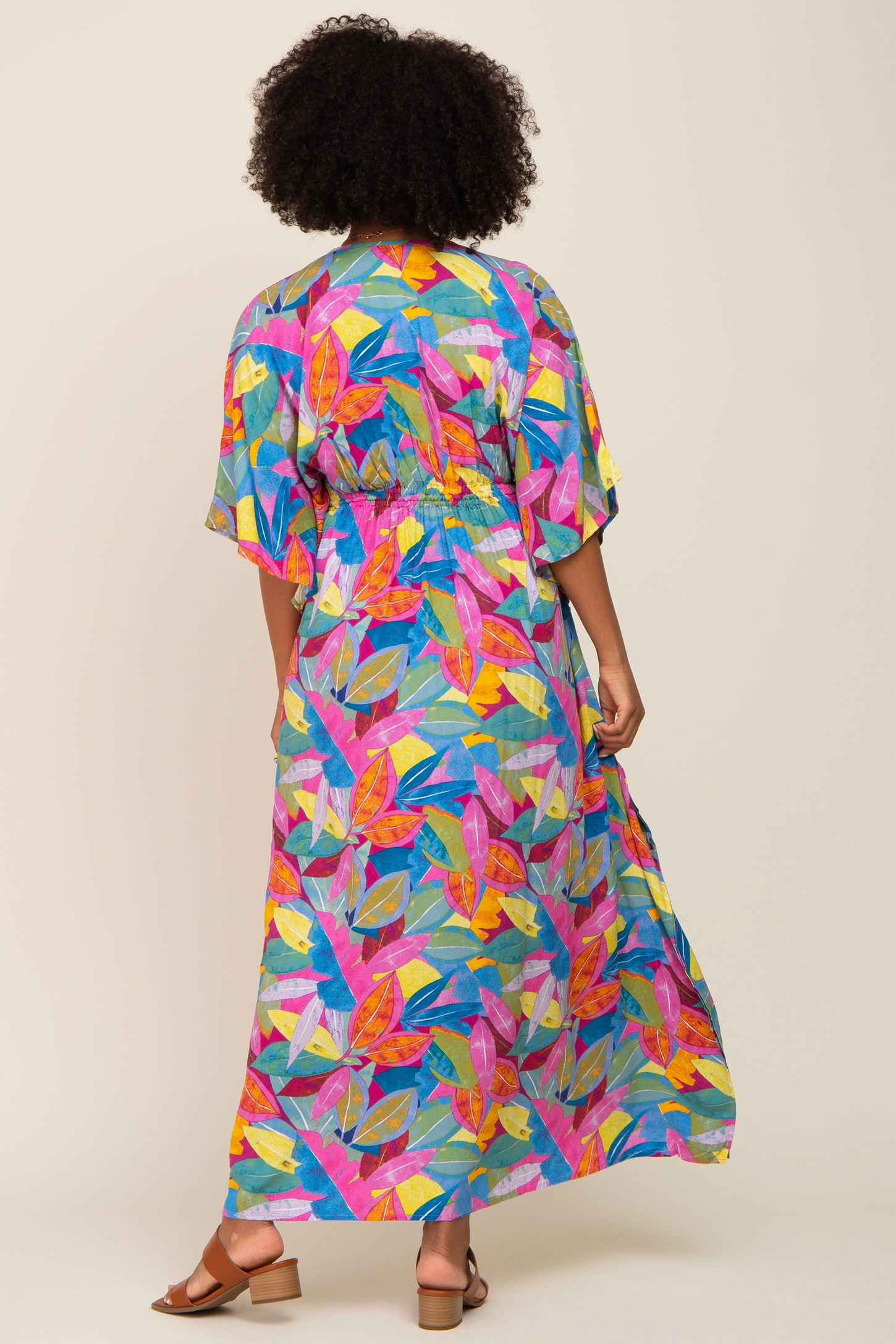 woman wearing a colorful floral print maxi dress with kimono sleeves and a cinched waist, shown from the back