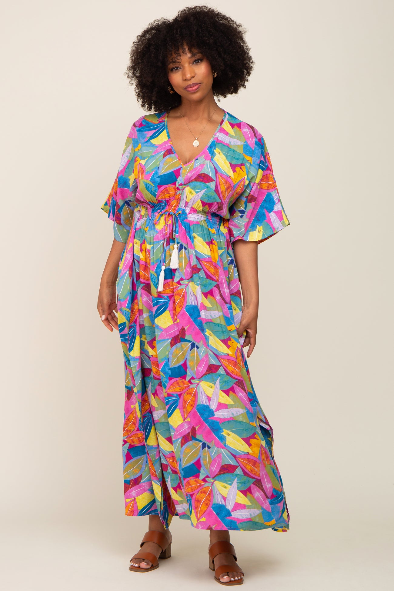woman wearing a colorful floral patterned maxi dress with a cinched waist and short flutter sleeves