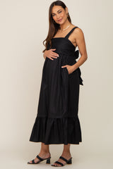 pregnant woman in a black sleeveless maternity midi dress with a ruffled hem and bow back detail