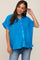 smiling pregnant woman wearing a blue pleated short sleeve button down maternity top and jeans