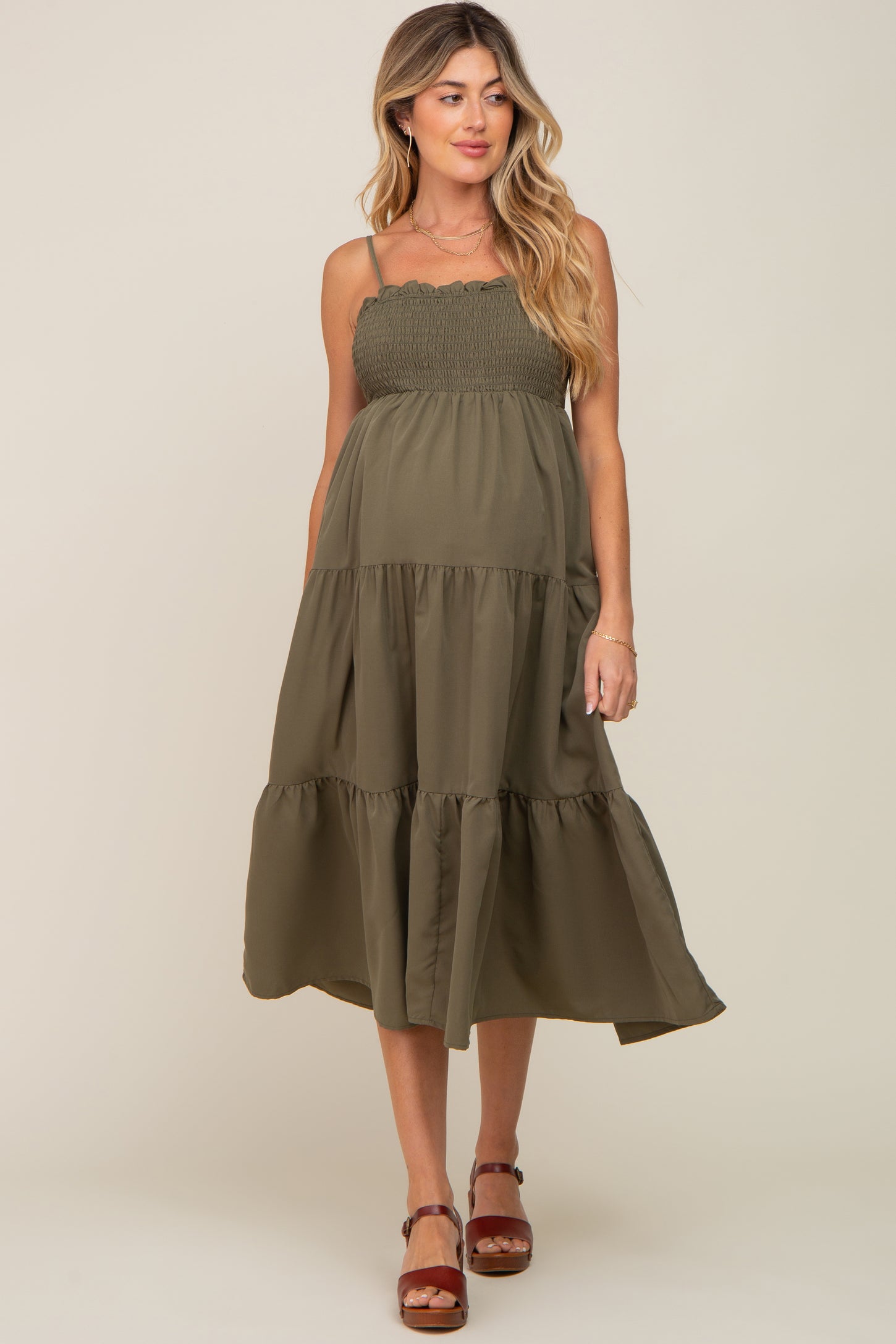 pregnant woman wearing an olive green smocked tiered maternity midi dress with spaghetti straps