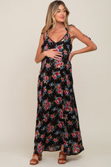 Pregnant woman wearing a black floral maternity maxi dress with tie straps and brown sandals