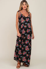 woman wearing a black floral maternity maxi dress with tie straps and brown sandals