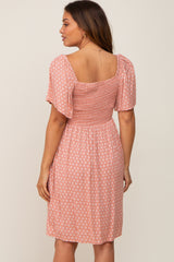 Woman wearing a pink patterned smocked back midi dress with flutter sleeves and a square neckline
