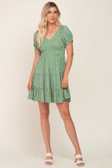 woman wearing a green floral smocked mini dress with short puff sleeves and tiered skirt