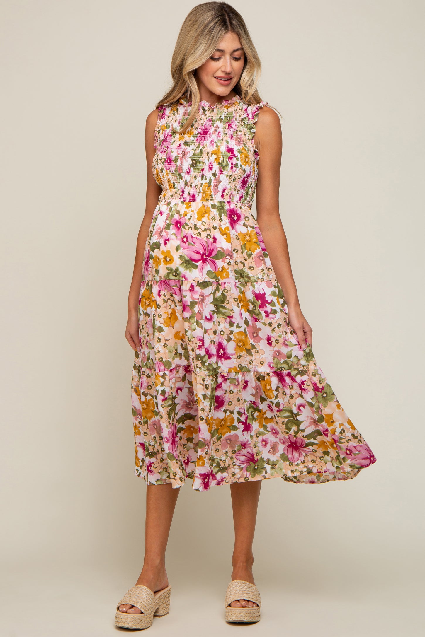 woman wearing a sleeveless floral smocked maternity midi dress with pink and yellow flowers