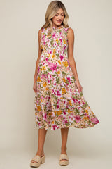 woman wearing a sleeveless floral smocked maternity midi dress with pink and yellow flowers
