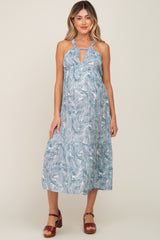 woman wearing a blue and white palm leaf print halter maternity midi dress with brown platform sandals