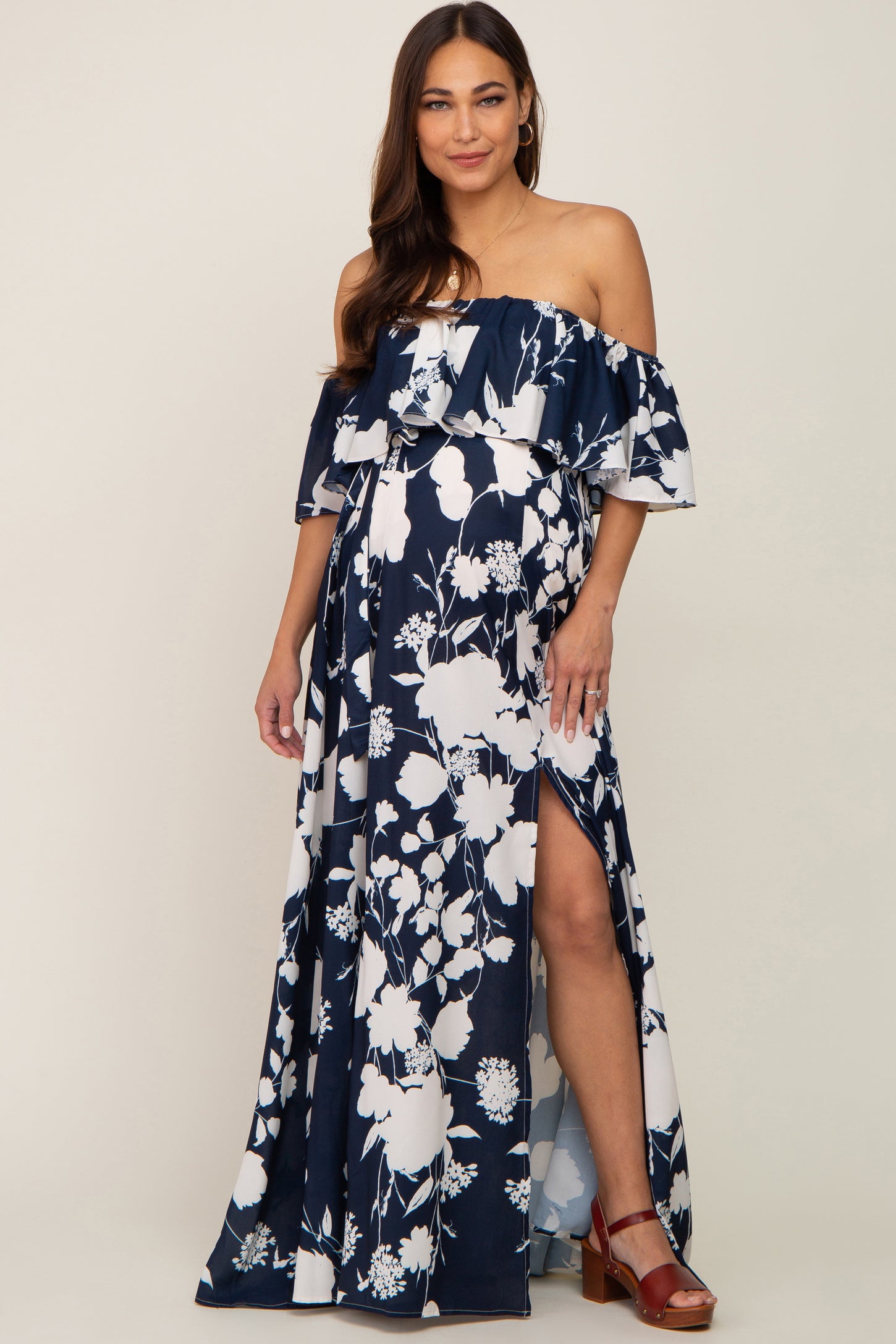 woman in navy blue and white floral off-the-shoulder maternity maxi dress with a leg slit