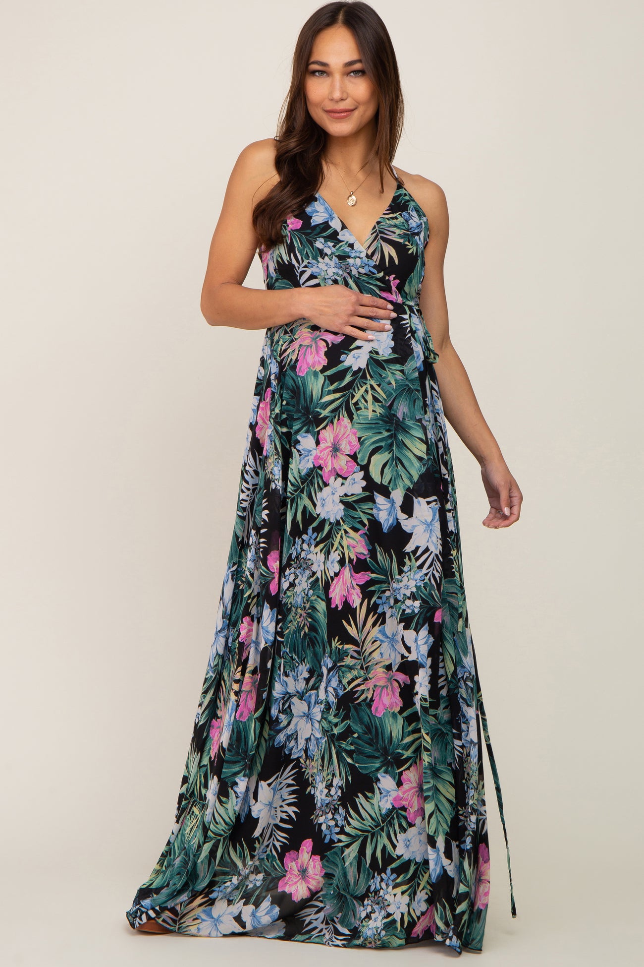 woman wearing a black floral maternity maxi dress and gently holding her baby bump