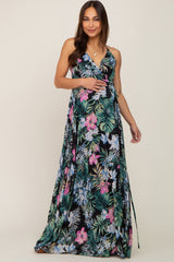 woman wearing a black floral maternity maxi dress and gently holding her baby bump