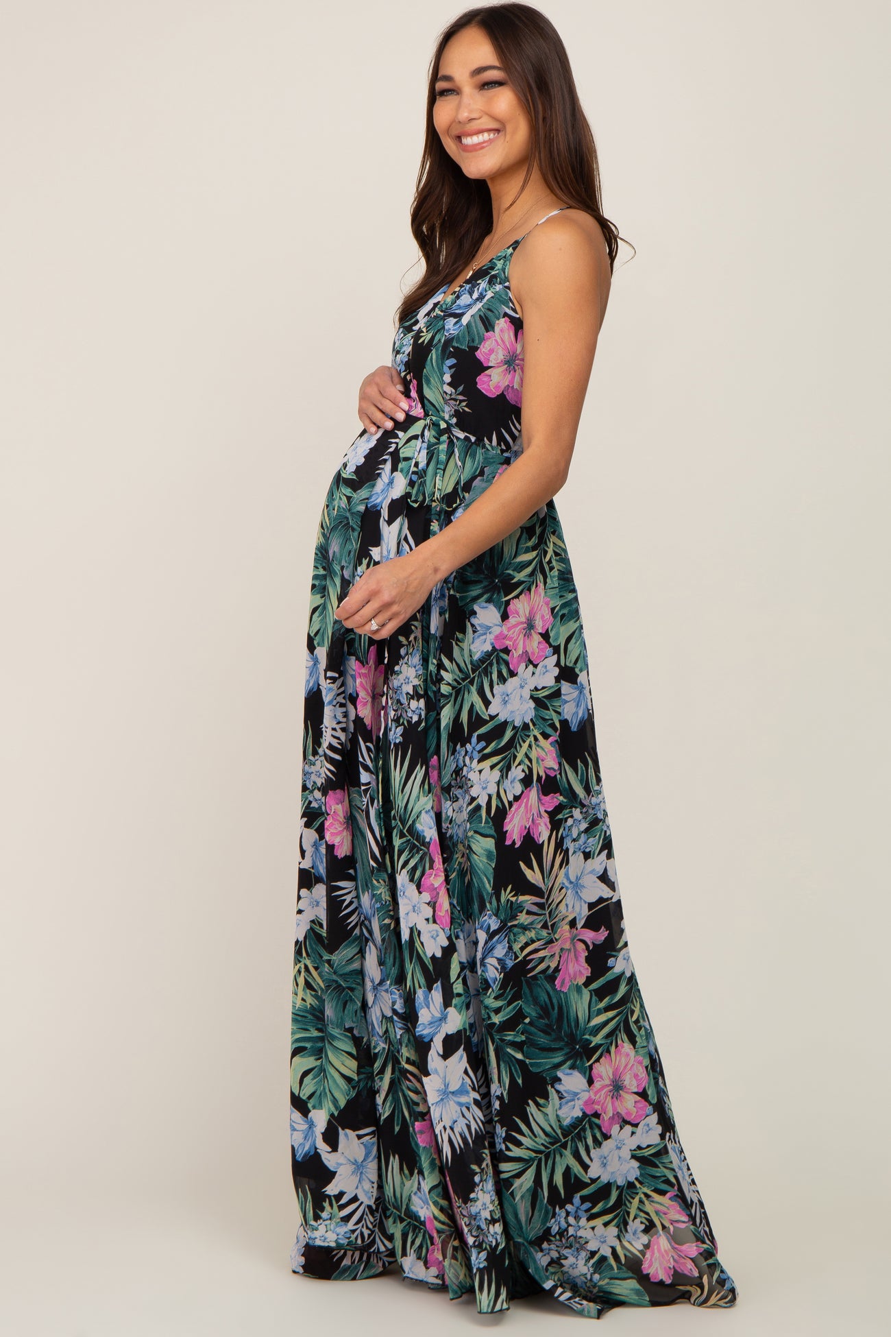 woman wearing a black floral maternity maxi dress and holding her baby bump