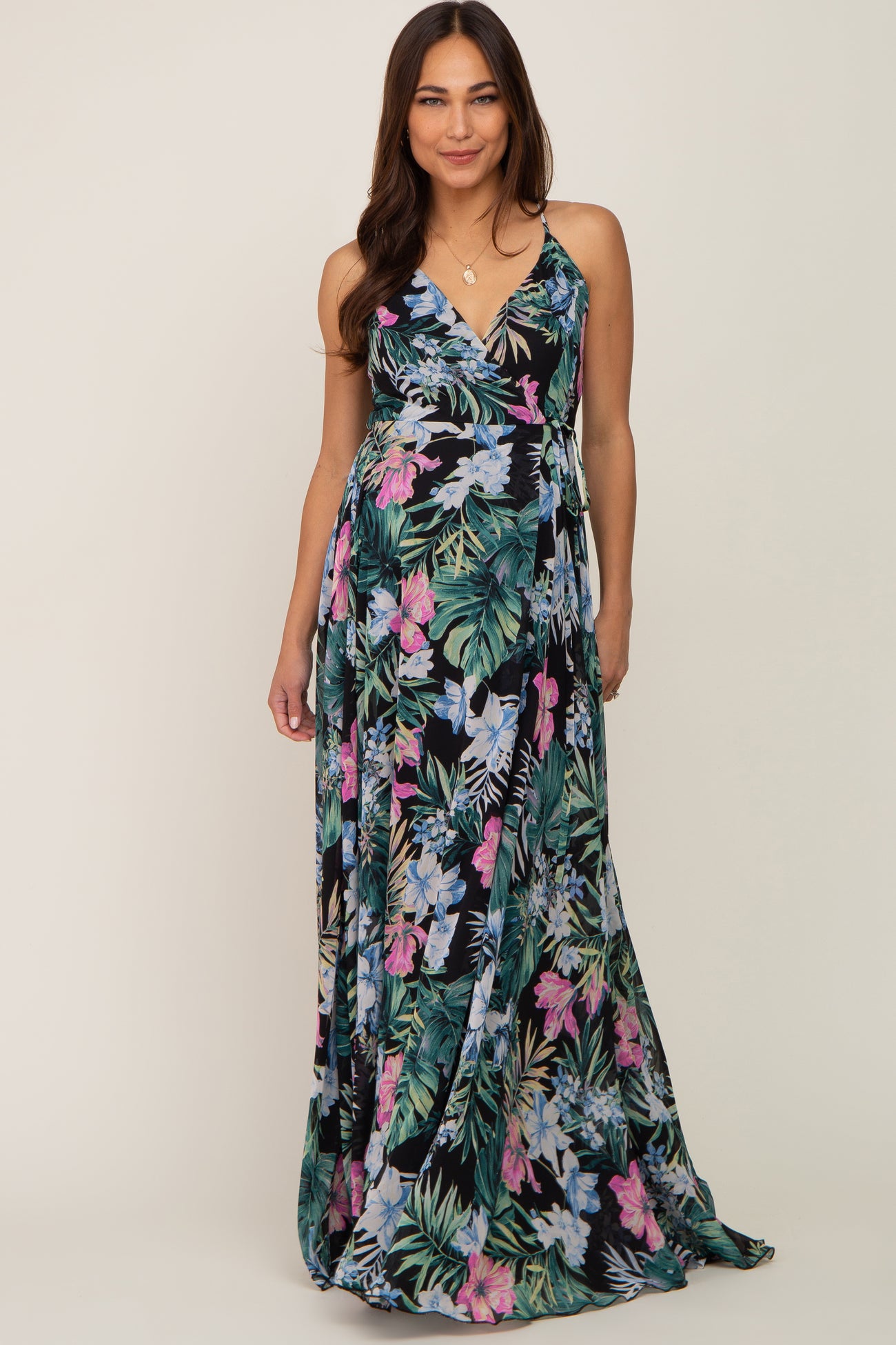 woman wearing a floral maxi maternity dress with a deep v-neck and adjustable straps, showcasing her baby bump