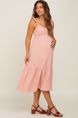 pregnant woman in a light pink ruffle sleeve maternity midi dress and brown sandals