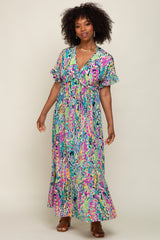 Woman with curly hair wearing a colorful floral print maxi dress with ruffle sleeves and brown sandals