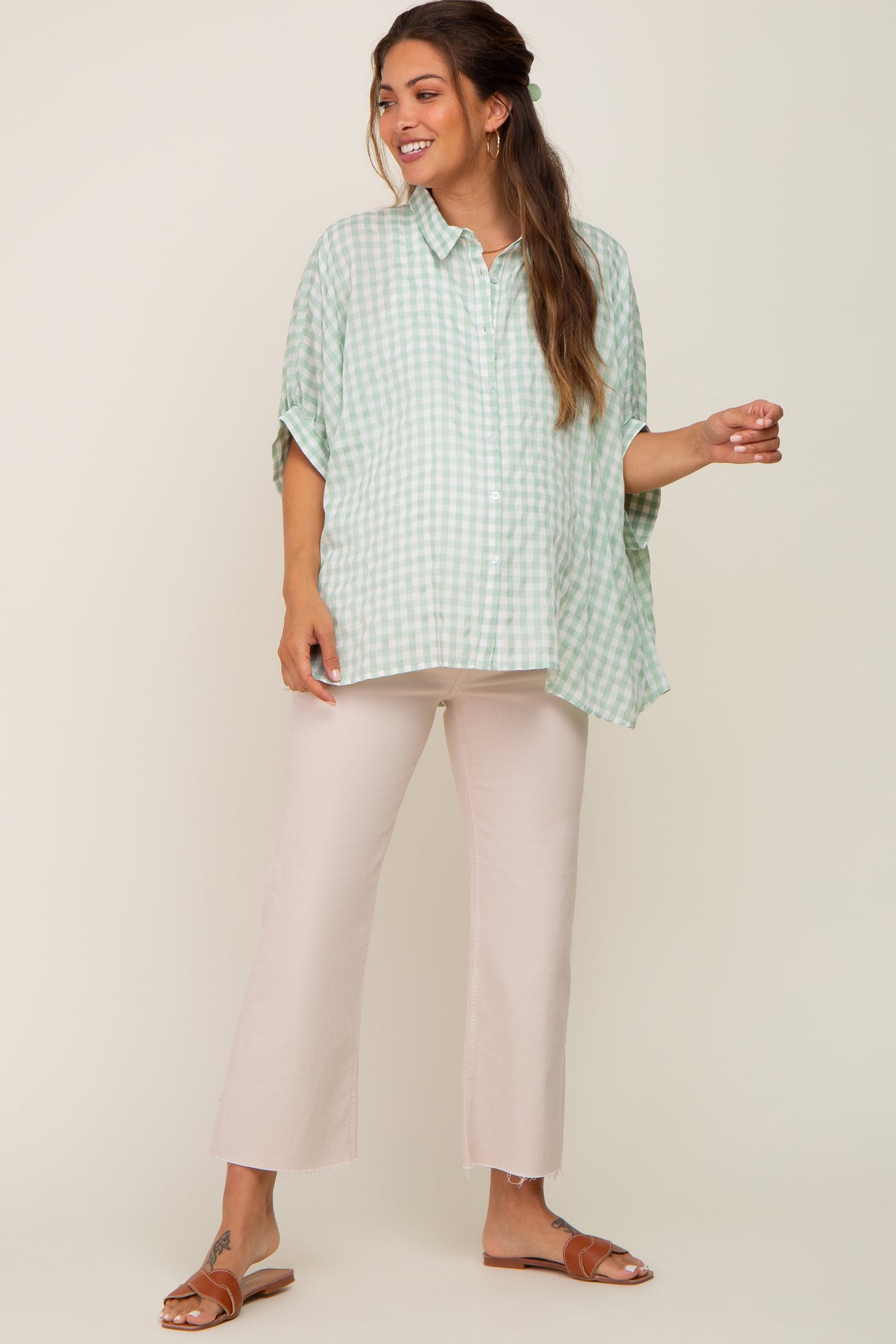 pregnant woman wearing a green gingham button down maternity shirt and tan pants