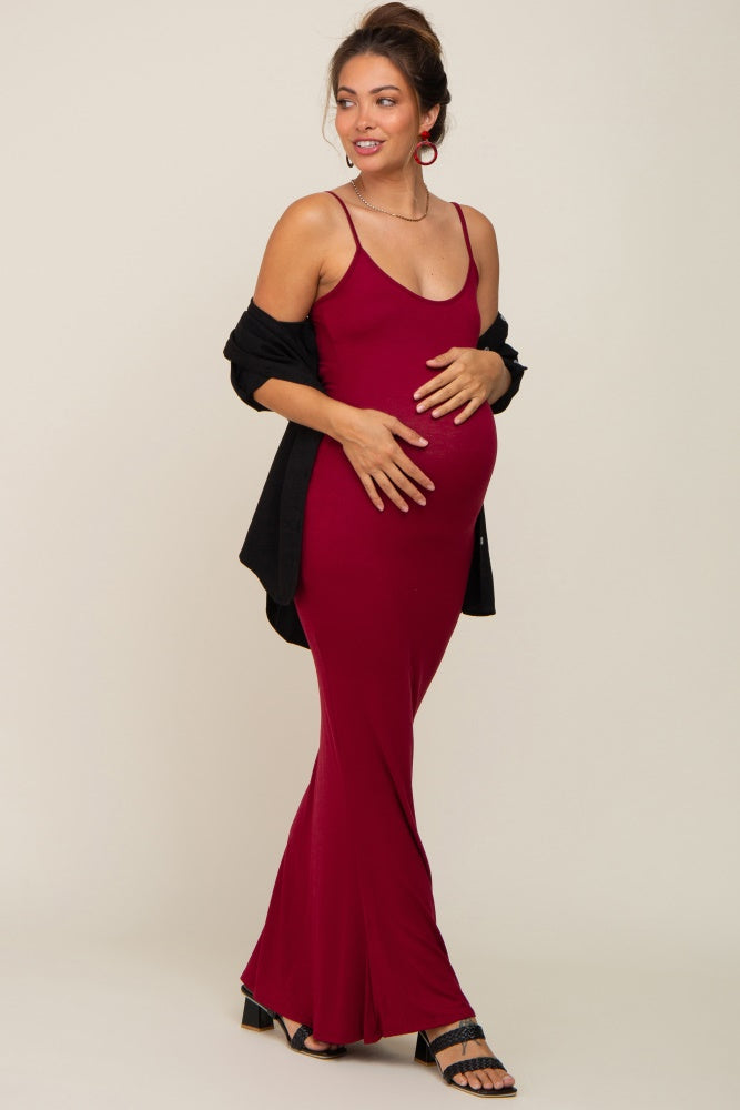 pregnant woman in a burgundy maternity maxi dress and black cardigan holding her baby bump