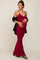 pregnant woman in a burgundy maternity maxi dress and black cardigan holding her baby bump