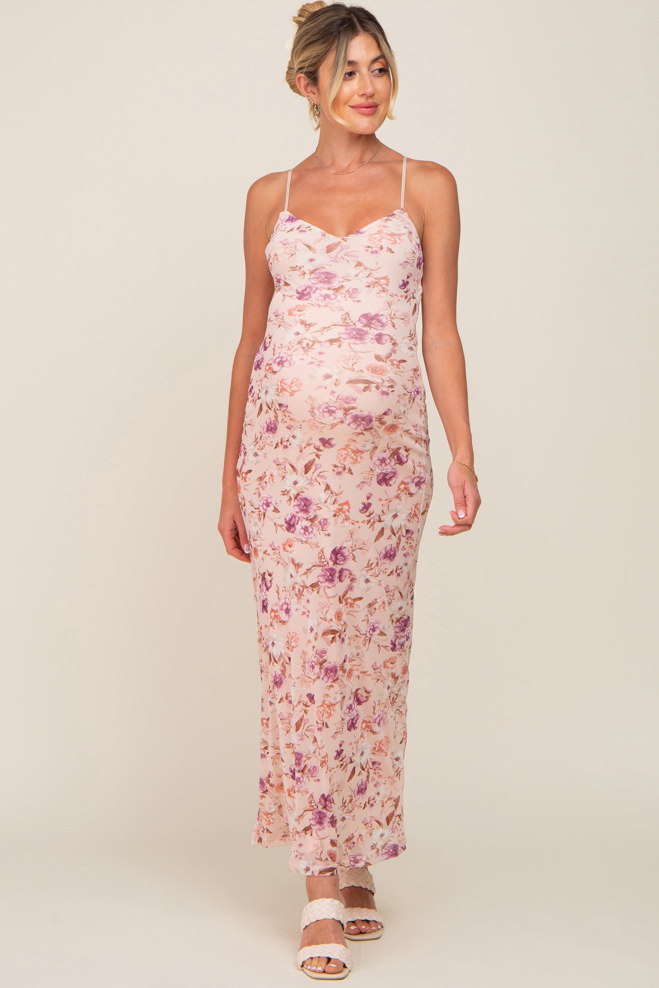 pregnant woman wearing a pink floral maternity maxi dress with spaghetti straps and white sandals
