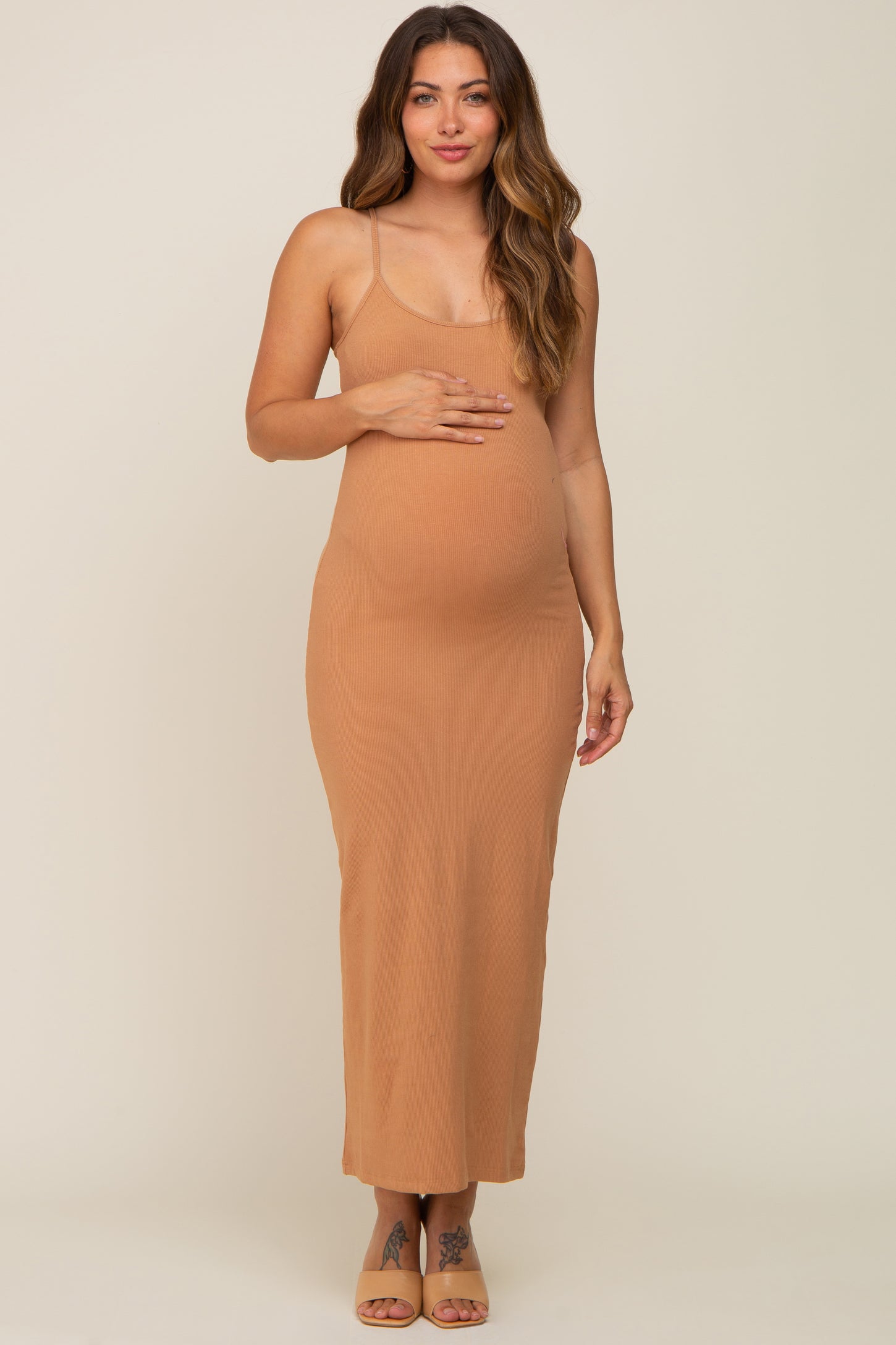 woman wearing a tan ribbed maternity maxi dress and cradling her baby bump