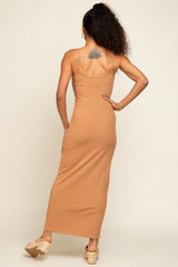 woman wearing a tan spaghetti strap maxi dress, view from the back showing a fitted silhouette and ankle-length.
