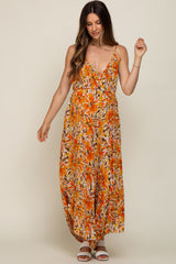 Woman wearing an orange floral print maternity maxi dress with spaghetti straps and white sandals