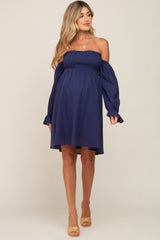 Pregnant woman wearing a navy blue off-the-shoulder smocked maternity dress with long sleeves
