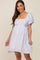 Smiling woman wearing a light blue and white floral maternity dress with puff sleeves and a square neckline