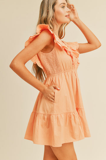 woman wearing a peach ruffled mini dress with smocked bodice and pockets