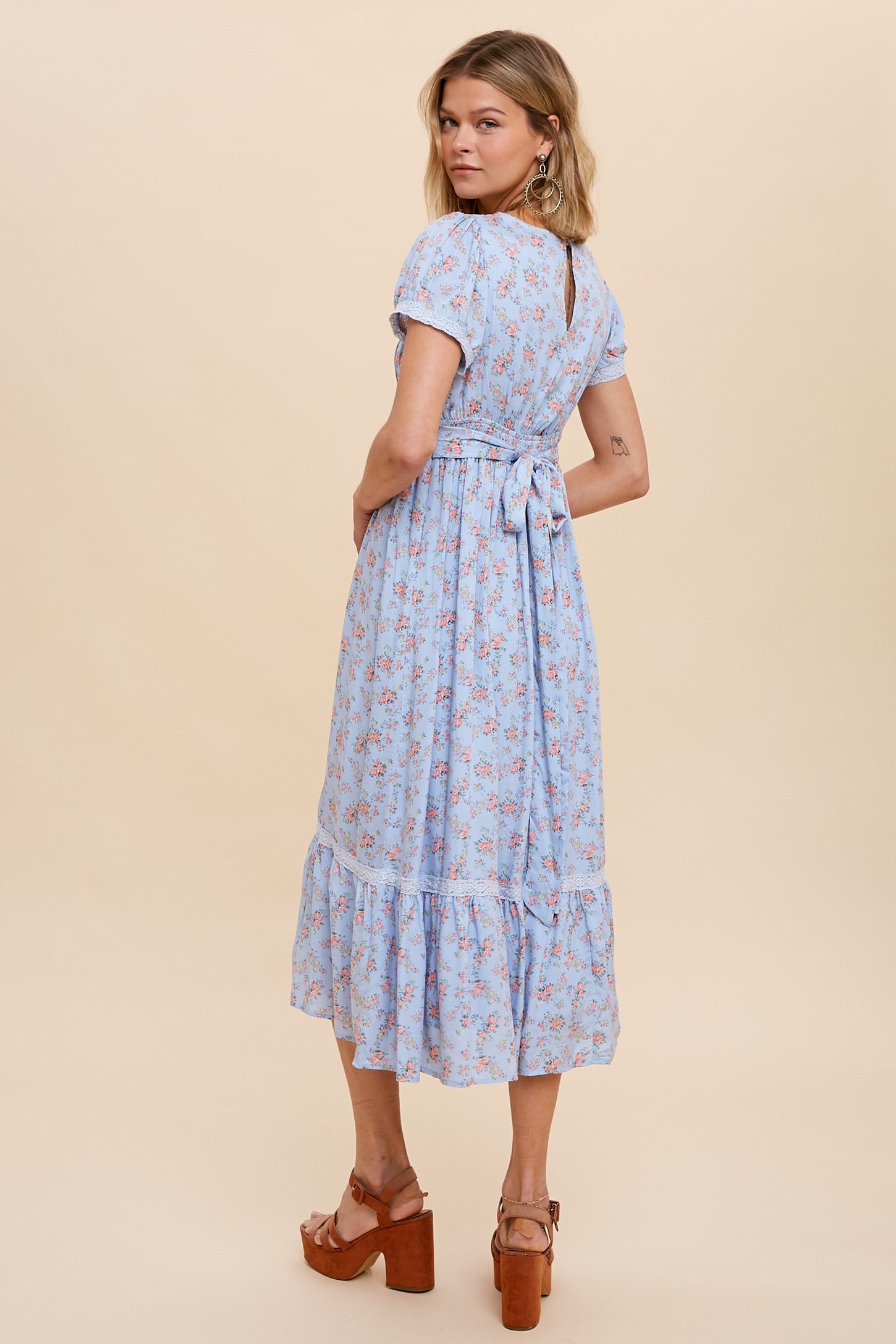 Woman wearing a light blue floral midi dress with short sleeves and brown platform sandals