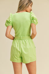 Back view of a woman wearing a lime green puff sleeve top and matching high-waisted shorts