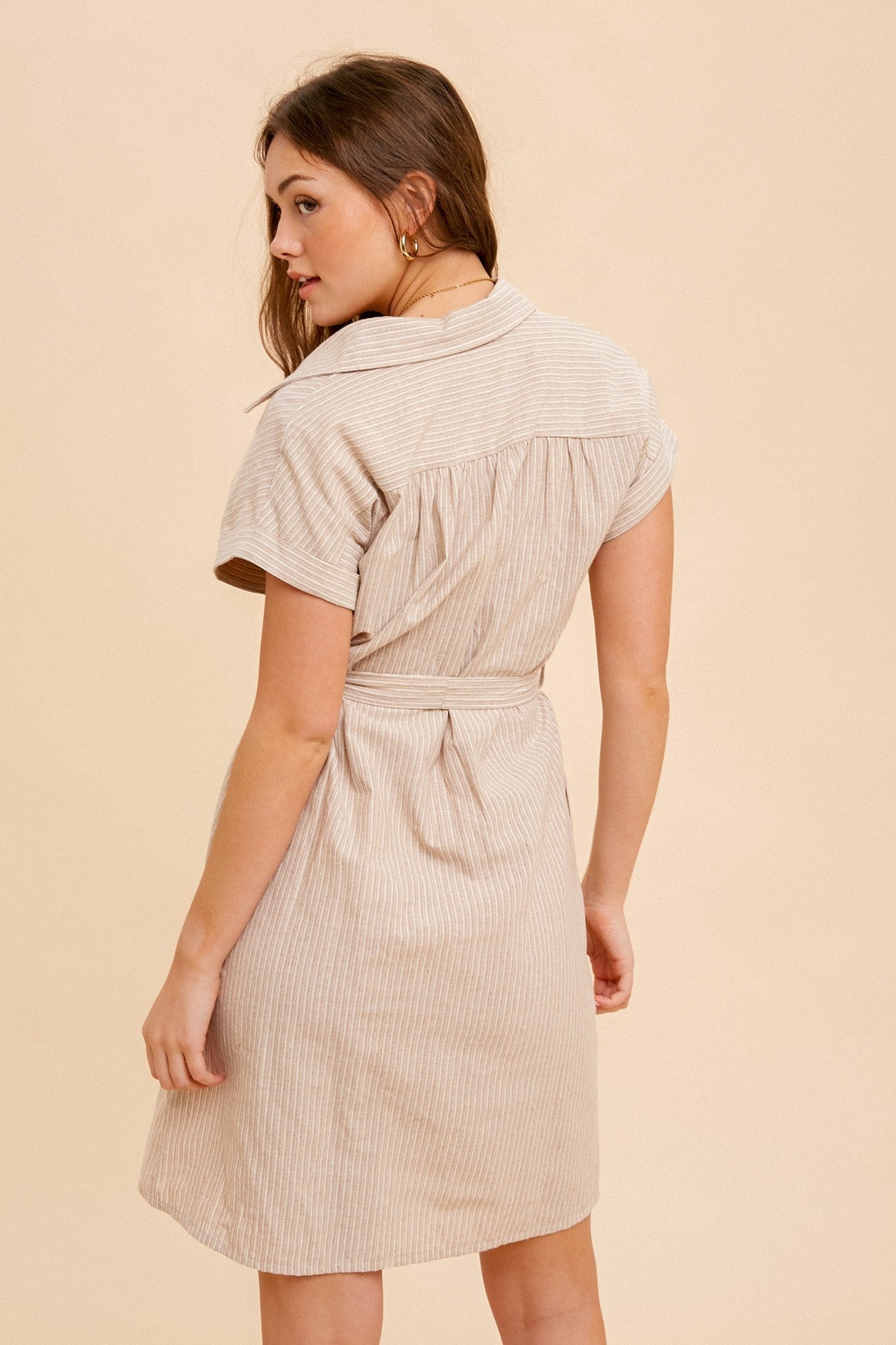 woman wearing a beige and white striped short sleeve shirt dress with a tie waist belt