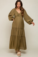 Pregnant woman wearing an olive green tiered maternity maxi dress with long puff sleeves and a v-neckline