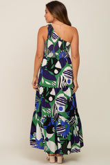 woman wearing a patterned one-shoulder maternity maxi dress with a tiered skirt, showing off a baby bump