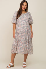 Woman wearing a grey floral tiered midi dress with puff sleeves and white sandals