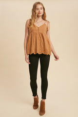 woman wearing a tan eyelet babydoll tank top with black skinny jeans and brown suede ankle boots