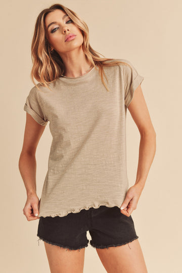 Woman wearing a beige short sleeve slub knit t-shirt and black denim shorts against a neutral background