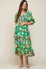 woman wearing a vibrant green floral maternity dress with puff sleeves and a baby bump visible