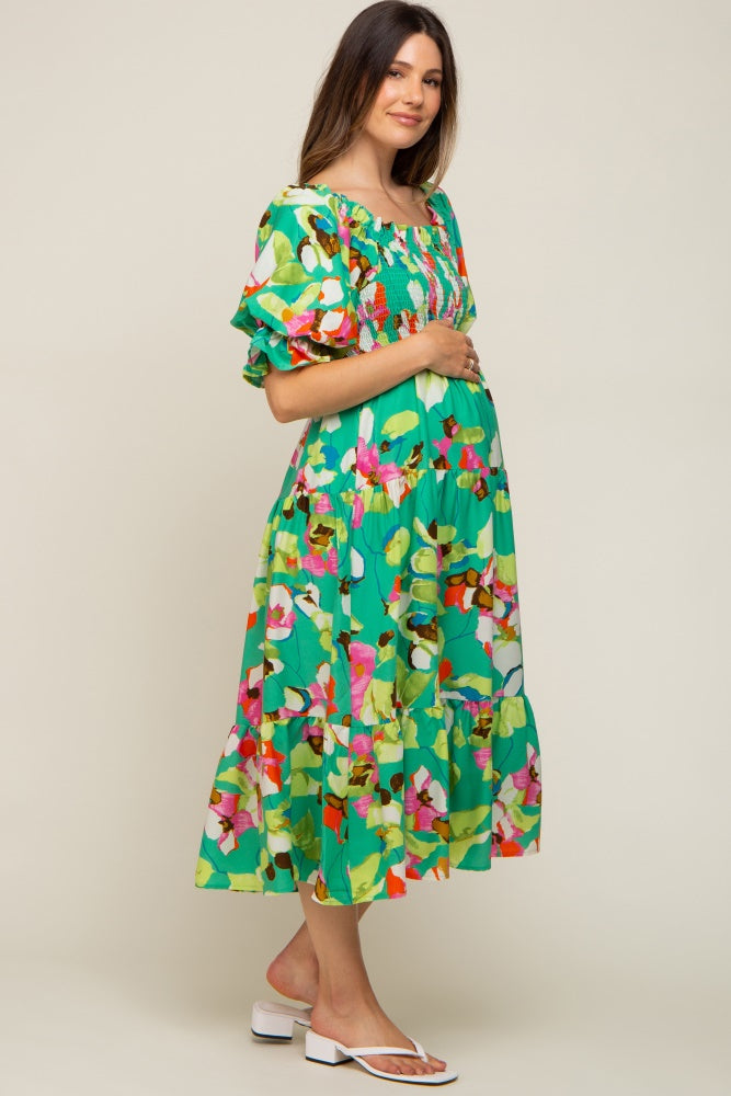 woman wearing a green floral maternity dress with puff sleeves and a visible baby bump