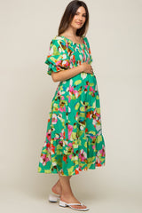 woman wearing a green floral maternity dress with puff sleeves and a visible baby bump